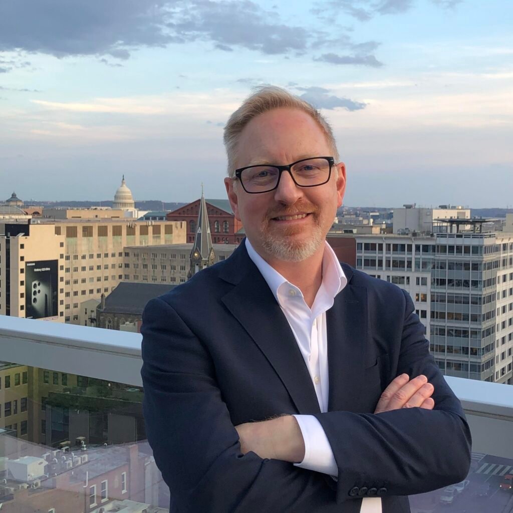 Man smiling on rooftop, city skyline background.