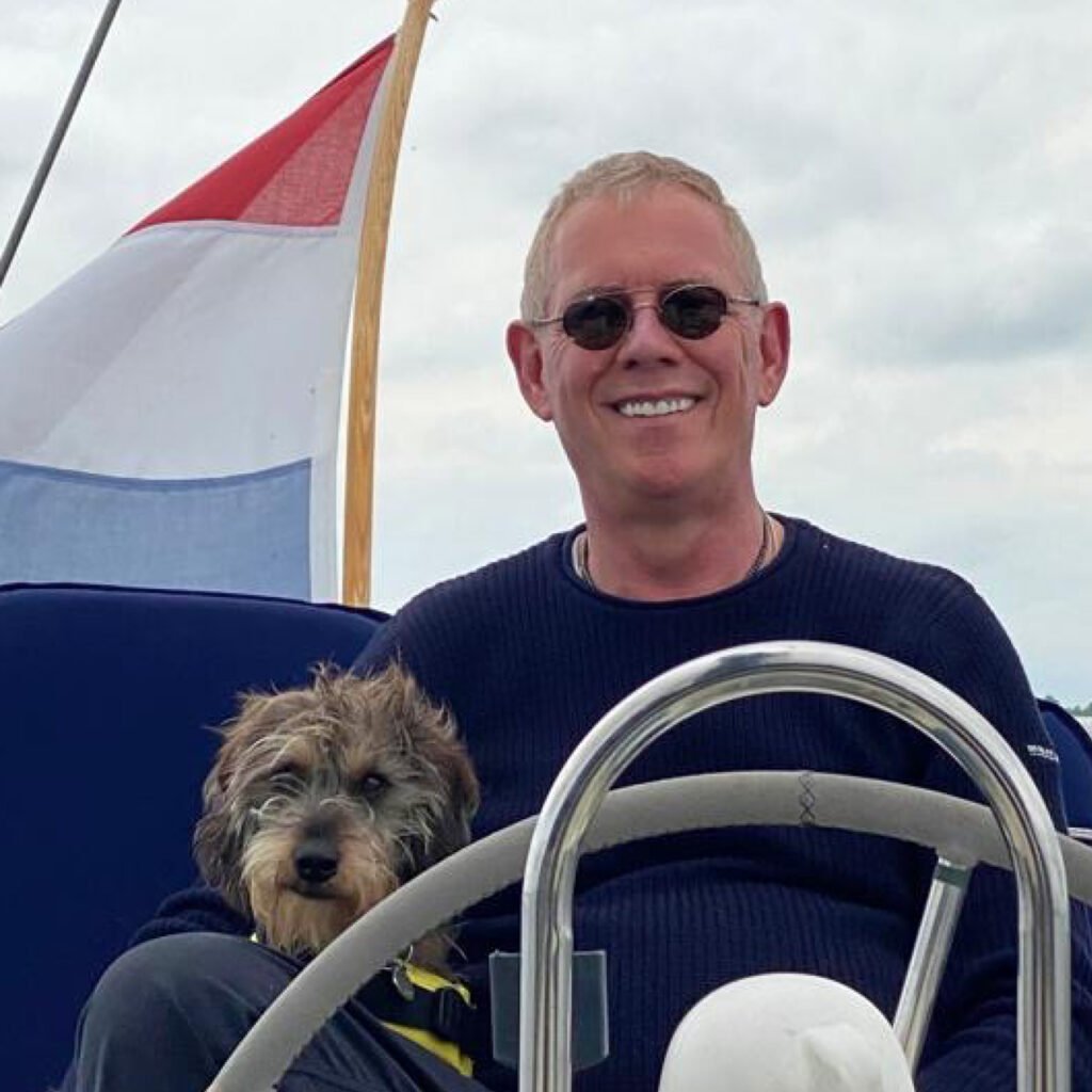 Man and dog sailing with flag in background.